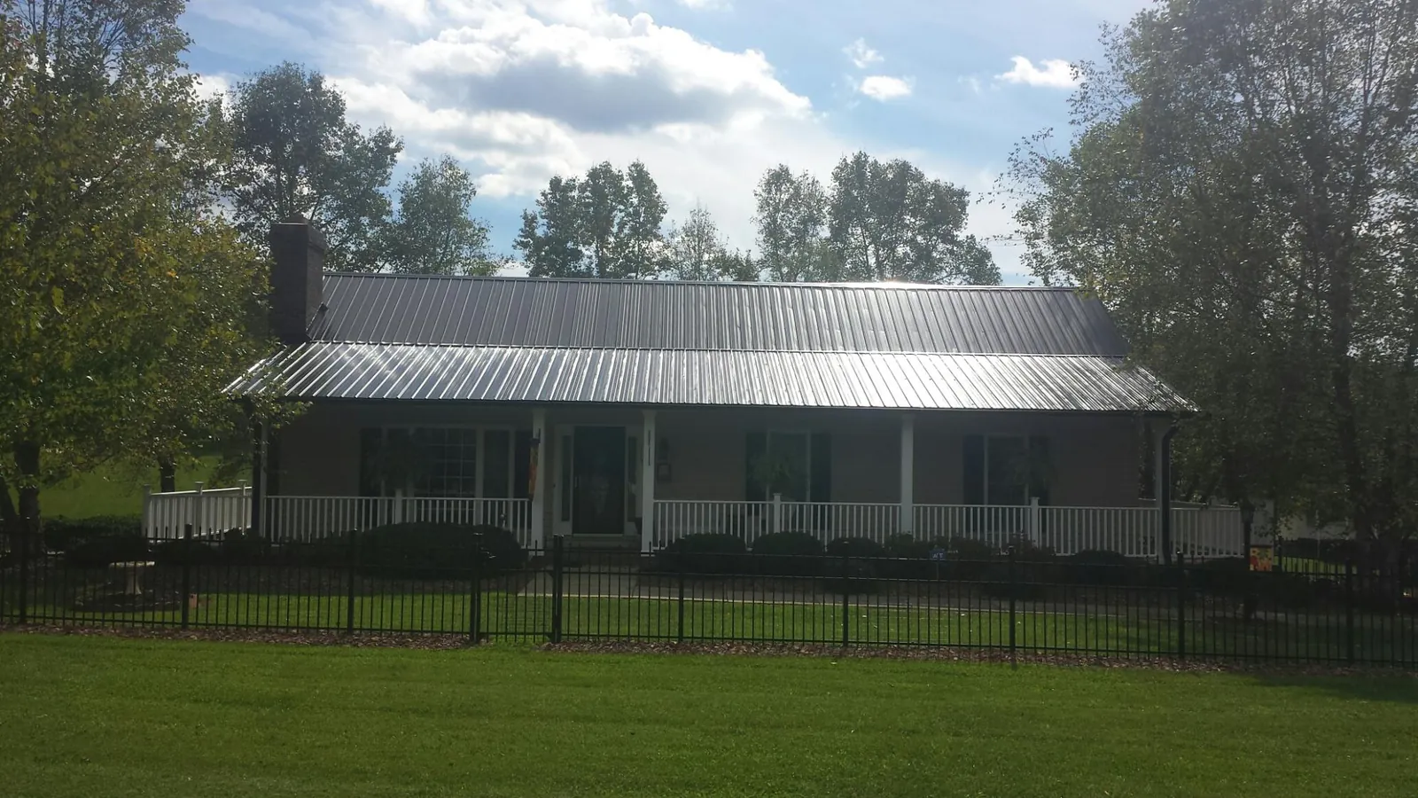 Gray metal roof on a brick ranch with a full width front porch — Gutter Guard Installation work by our crew in La Crosse
