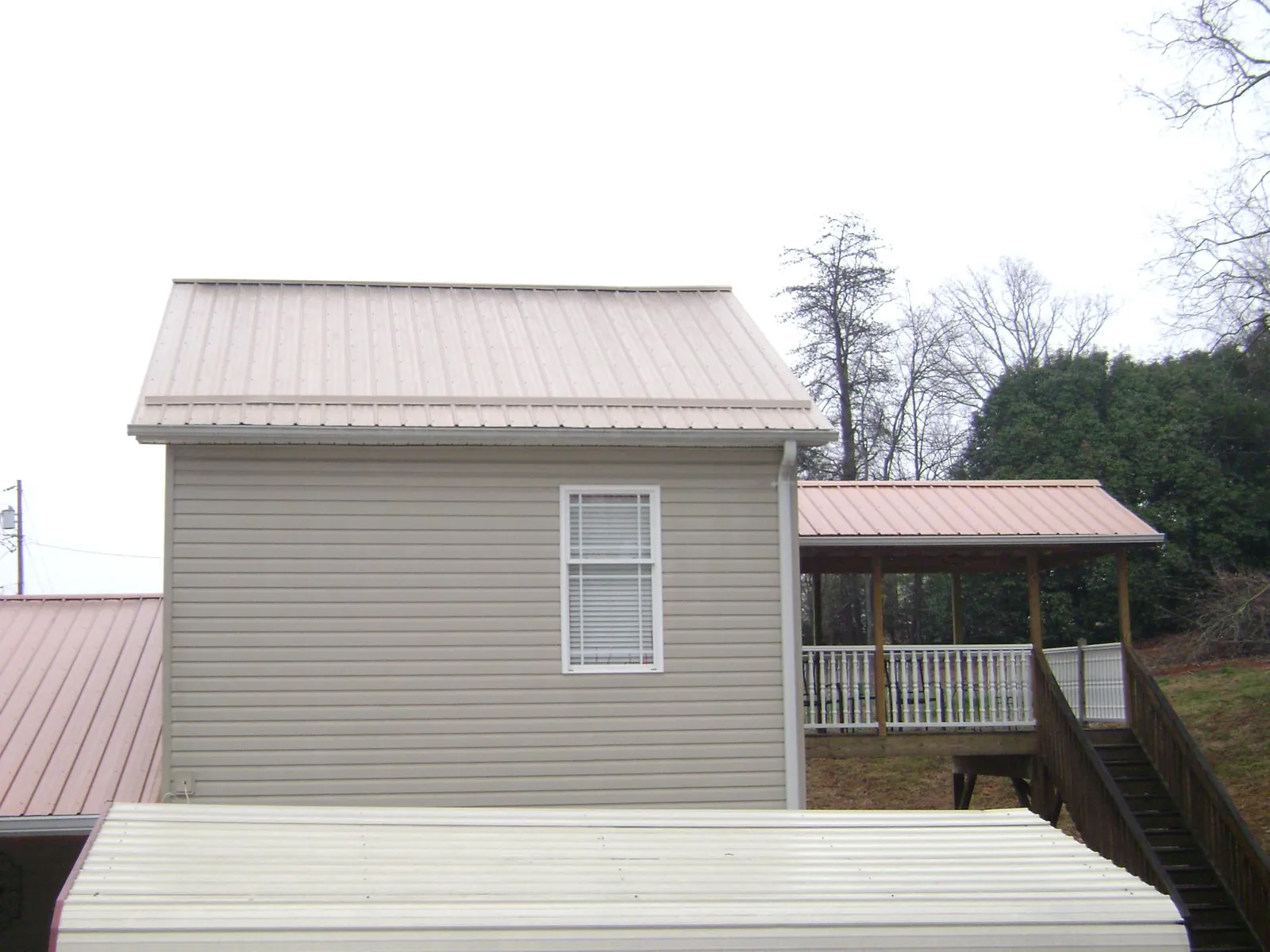 Tan metal roofs on a two story addition and attached porch, from a Roof Replacement job in La Crosse